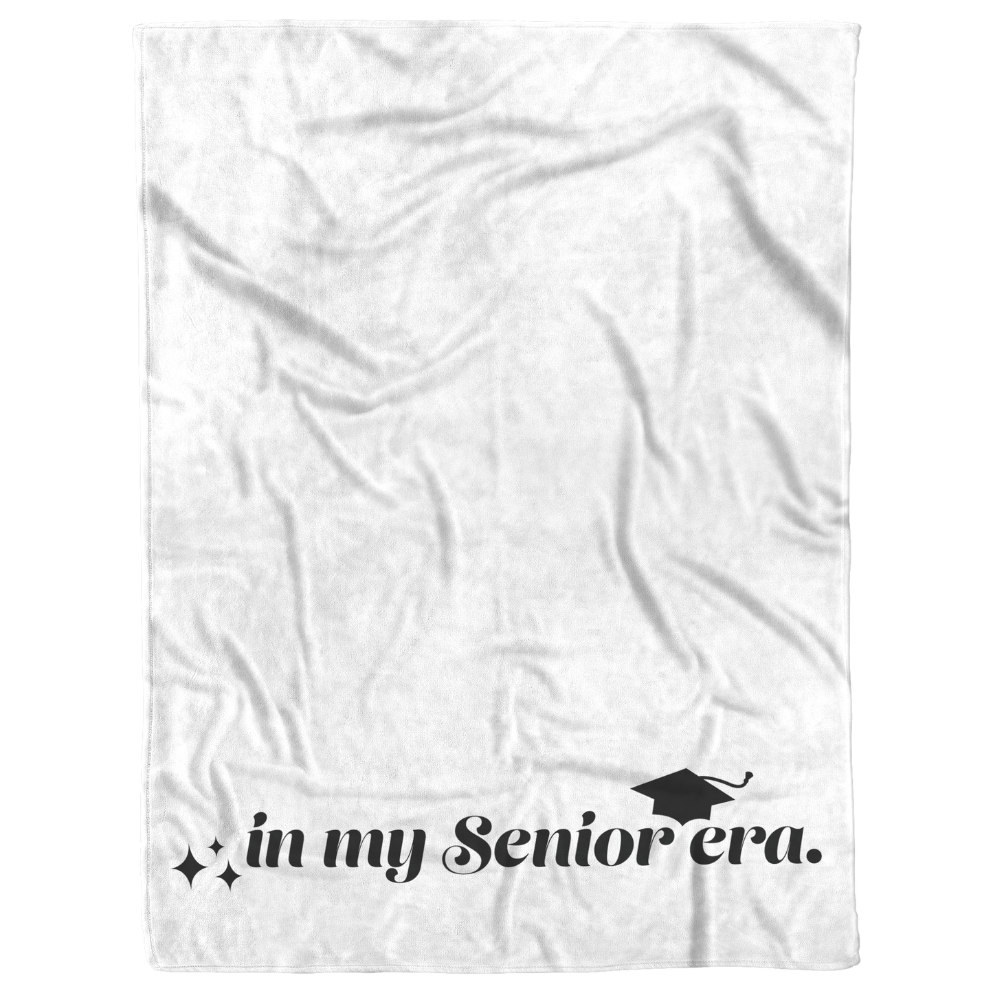A white fleece blanket with the phrase "In My Senior Era" and a graduation cap in black at the bottom laying flat.