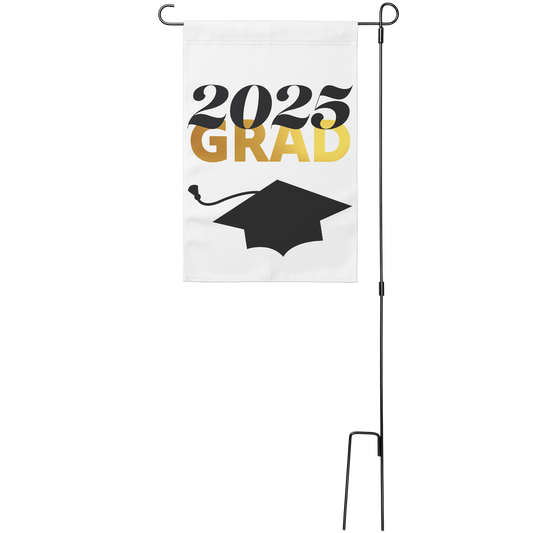 White garden flag with 2025 in black text, "Grad" in gold underneath, and a black graduation cap at the bottom. Sign hung from a wire stand. 