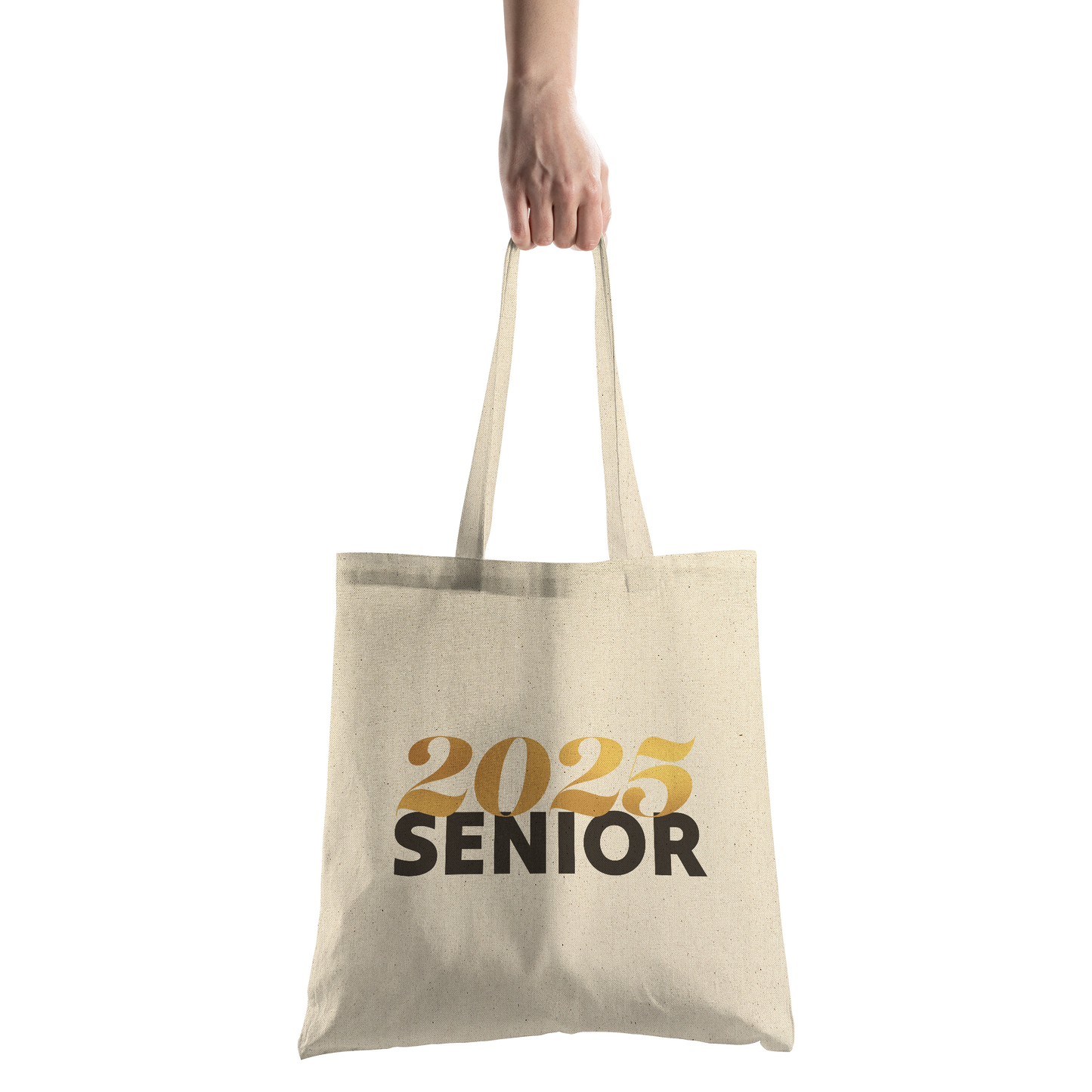 Tan canvas tote bag with 2025 in gold and senior in black being held by a hand